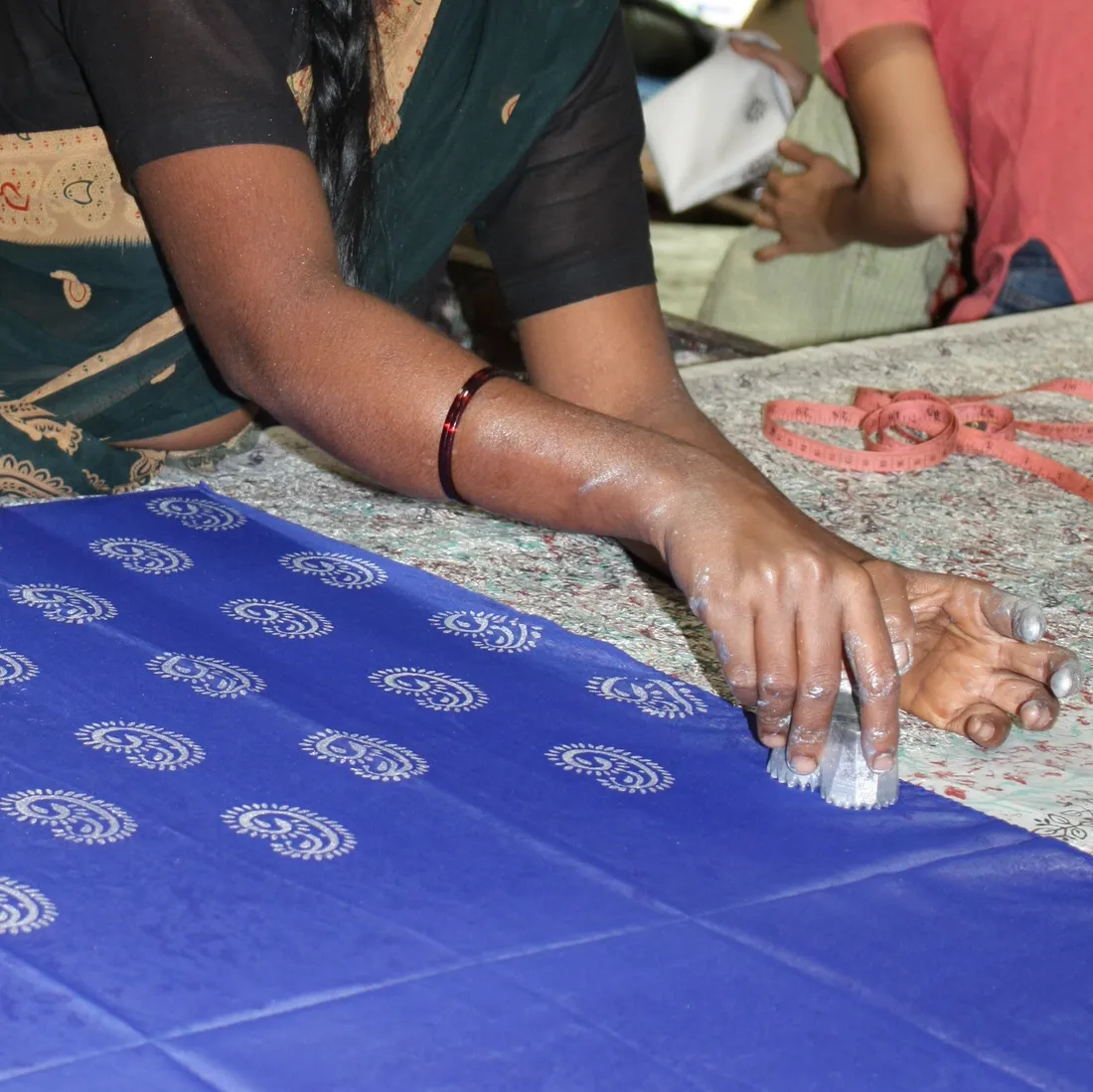 Hand block-printing on cotton with a carved wooden block at Halasur in Karnataka — the printing and dyeing craft carried alongside tailoring in the Chippiga, Chippolu and Simpi community