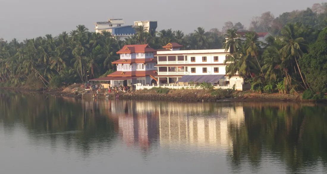 The Parassini Madappura Sree Muthappan temple seen across the Valapattanam river at Parassinikkadavu in Kannur district, coconut palms along the far bank