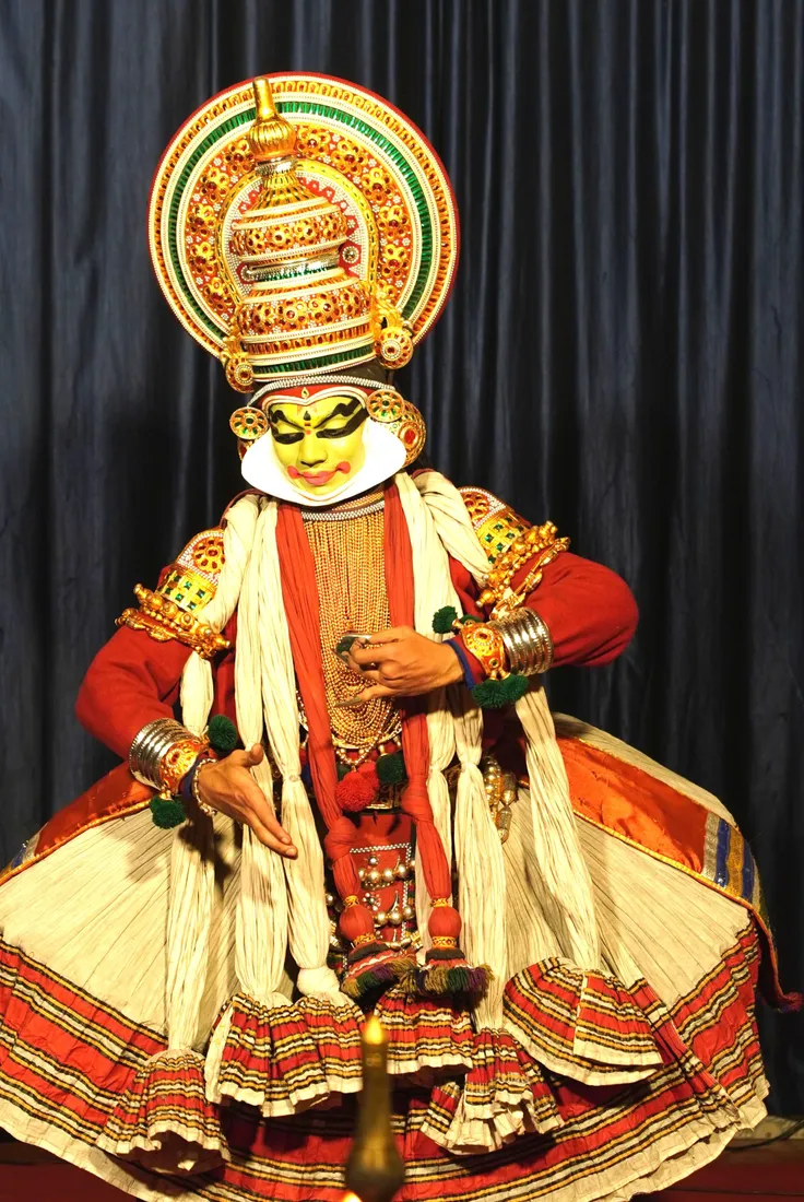 A Kathakali artist in the green Pachcha make-up and full kireedam headdress of Kerala's classical dance drama, performed beside a lit brass lamp