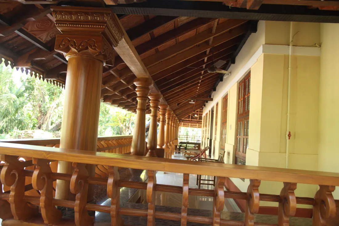 The carved wooden pillars, scrolled balustrade and rafters of the verandah of a Kerala nalukettu, the taravad house of a Nair family
